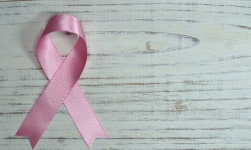 pink breast cancer ribbon on wooden surface