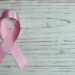 pink breast cancer ribbon on wooden surface