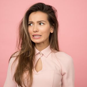woman with long hair standing in front of pink background