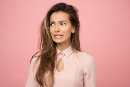 woman with long hair standing in front of pink background