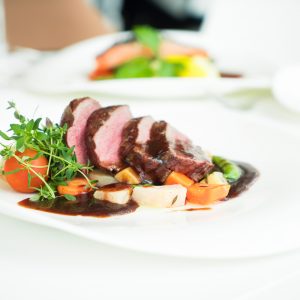 roast beef and roasted vegetables on a white plate