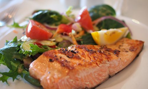 salmon fillet with side salad on white plate