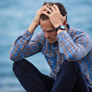 man sitting with hands on head looking stressed