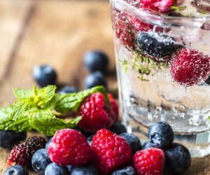 sparkling clear drink in a glass with floating berries inside