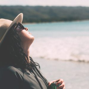 woman on a beach tilting her face toward the sun