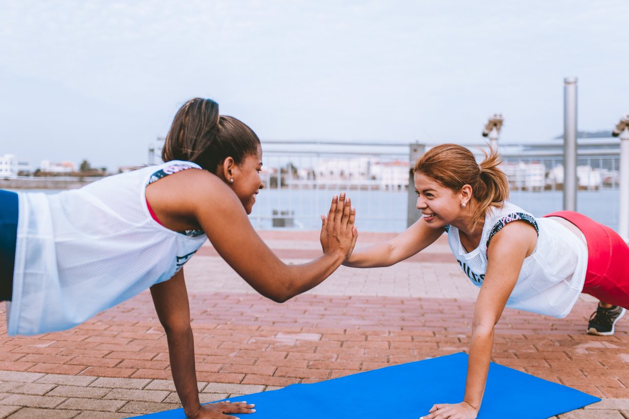 two woman holding planks and high-fiving each other