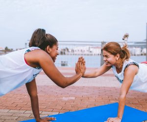 two woman holding planks and high-fiving each other