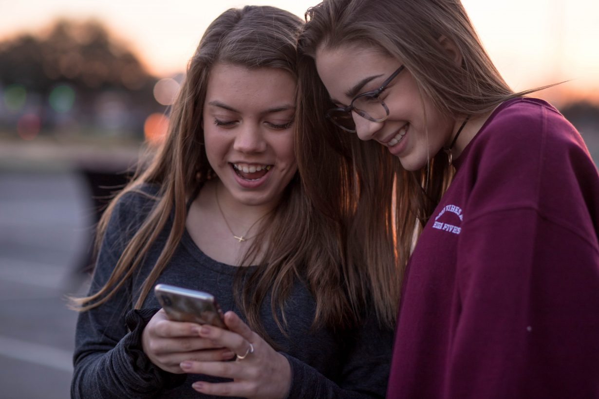 two teenage girls looking at a cell phone