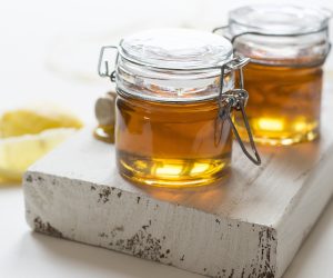 two jars of honey on a white plank