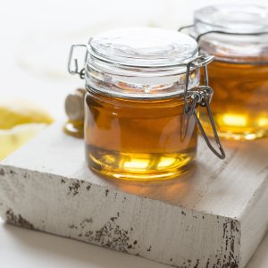two jars of honey on a white plank