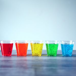 5 glasses lined up with rainbow colored fizzy drinks