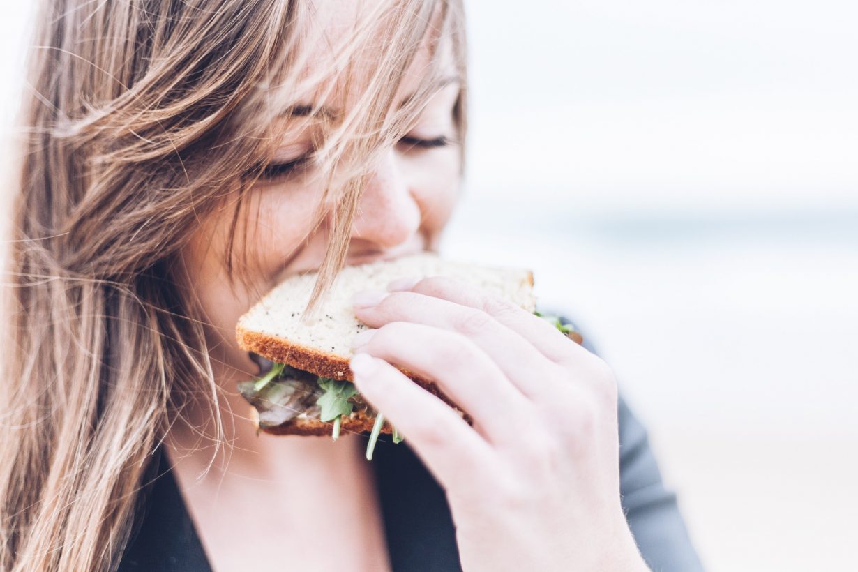 close up of a woman eating a sandwich