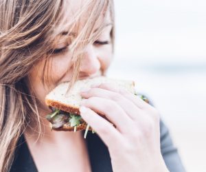 close up of a woman eating a sandwich