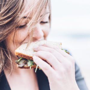 close up of a woman eating a sandwich