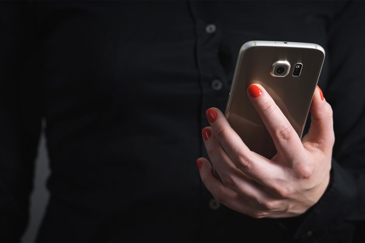 woman in a black shirt holding a smart phone