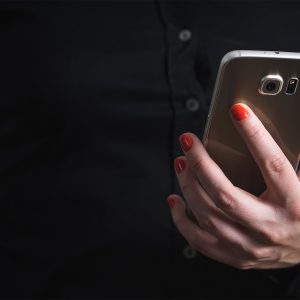woman in a black shirt holding a smart phone