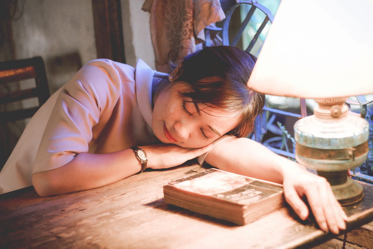 woman asleep with her head slouching on a desk
