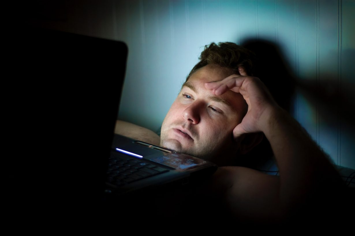 man looking at a computer screen in the dark
