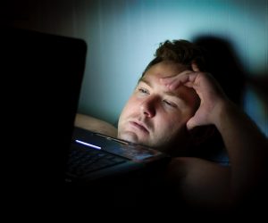man looking at a computer screen in the dark