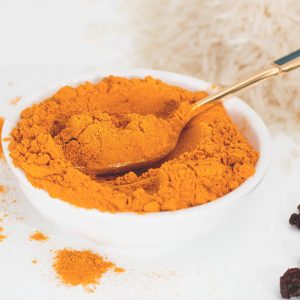 turmeric powder in a white bowl with a silver spoon