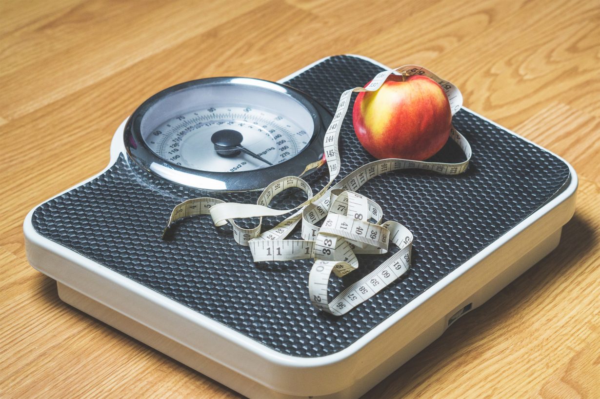 scale with measuring tape and an apple on it