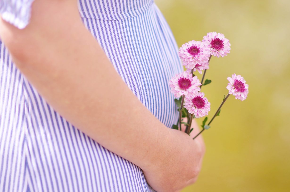 pregnant woman holding flowers against her belly