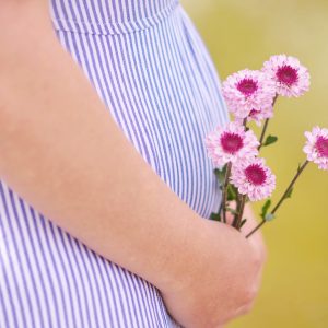 pregnant woman holding flowers against her belly