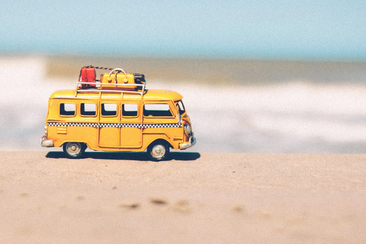 tiny bus on the sand in front of the ocean