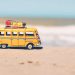 tiny bus on the sand in front of the ocean