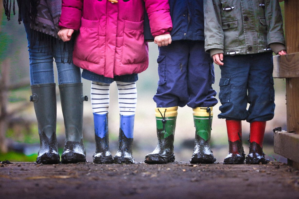 image of the legs of 4 children wearing rain boots
