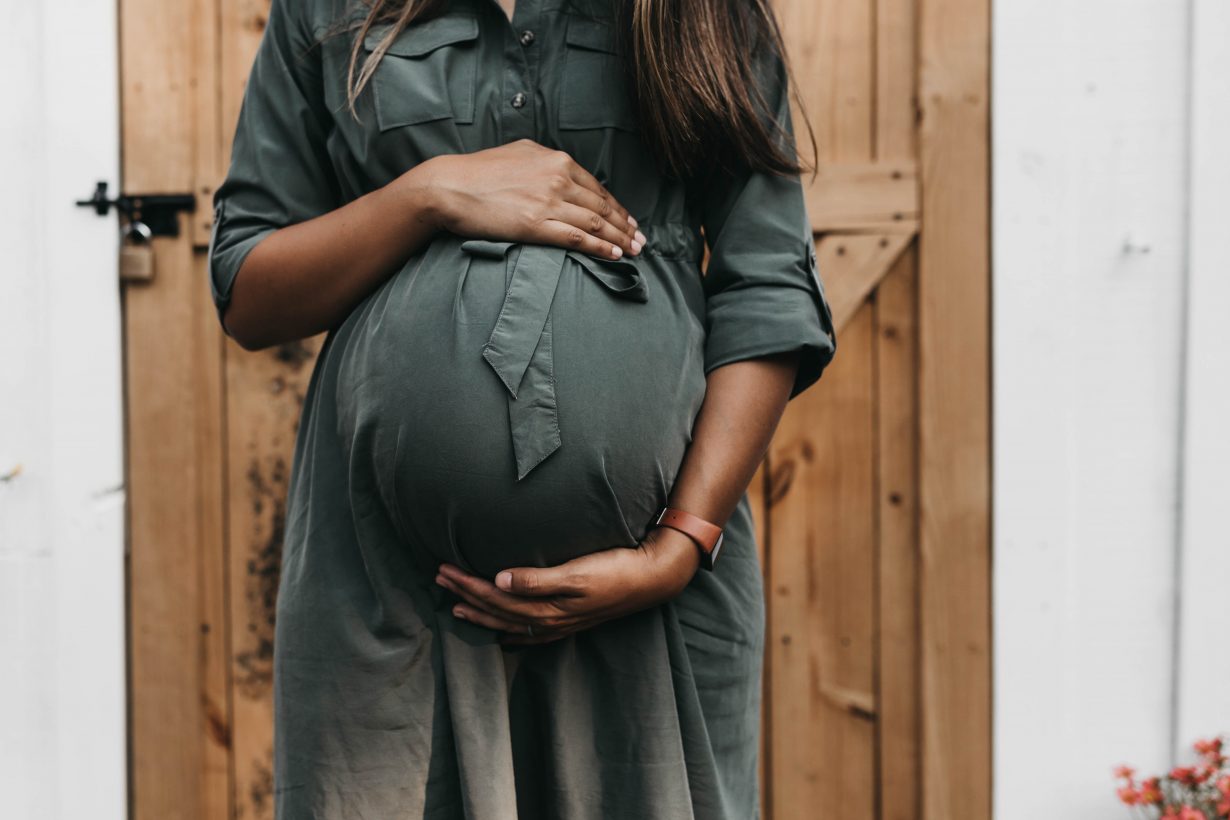 pregnant woman in a dress holding her belly