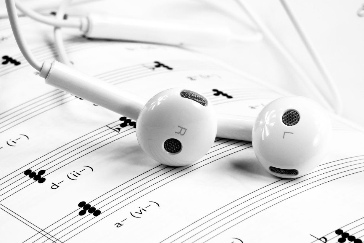 white headphones sitting on sheet music