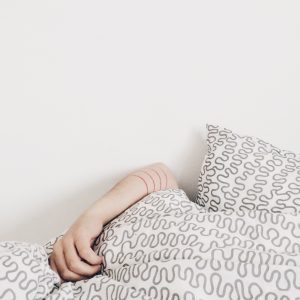 person's arm sticking out over a pile of bed pillows