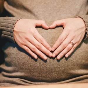 pregnant woman forming a heart with her hands over her tummy