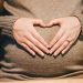 pregnant woman forming a heart with her hands over her tummy