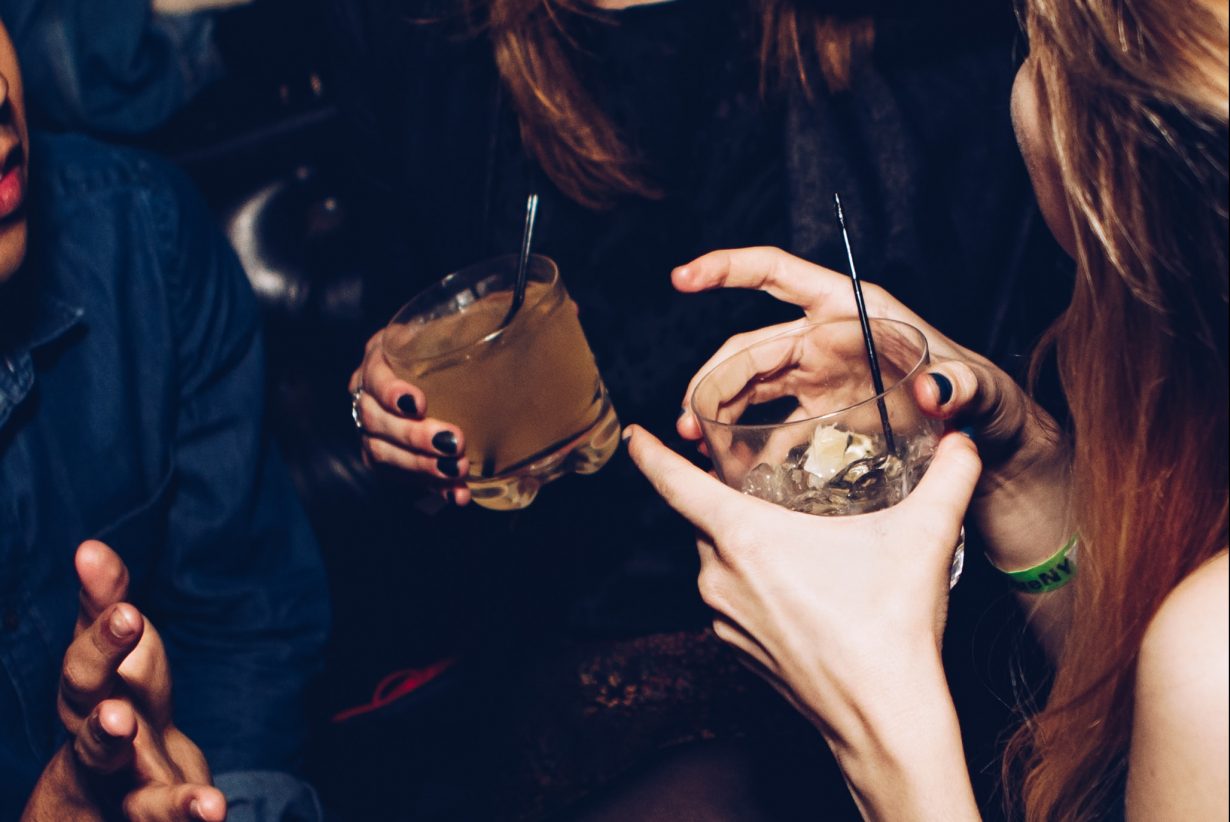 two people holding mixed drinks in their hands