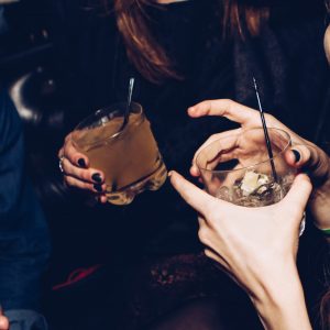 two people holding mixed drinks in their hands