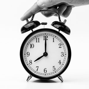 black and white photo of hand pushing a bell alarm clock