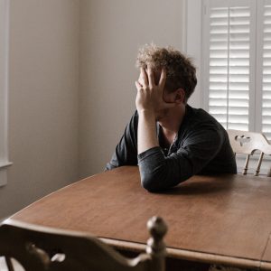 tired man leaning his head in his hands on a table