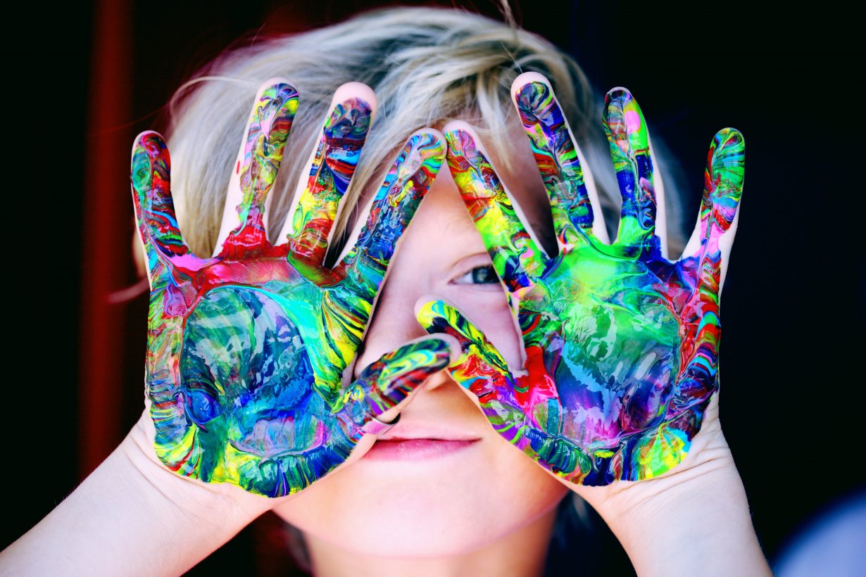 child holding up his hands with paint all over them