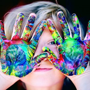 child holding up his hands with paint all over them