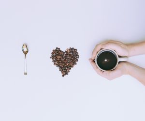 I love coffee spelled using a spoon, a heart made of coffee beans and a person holding a cup of coffee