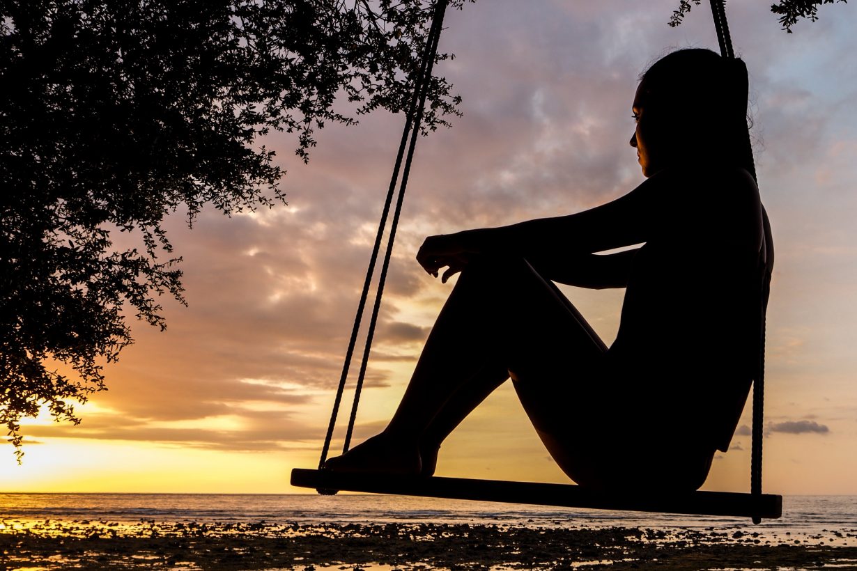 silhouette of a woman sitting on a swing