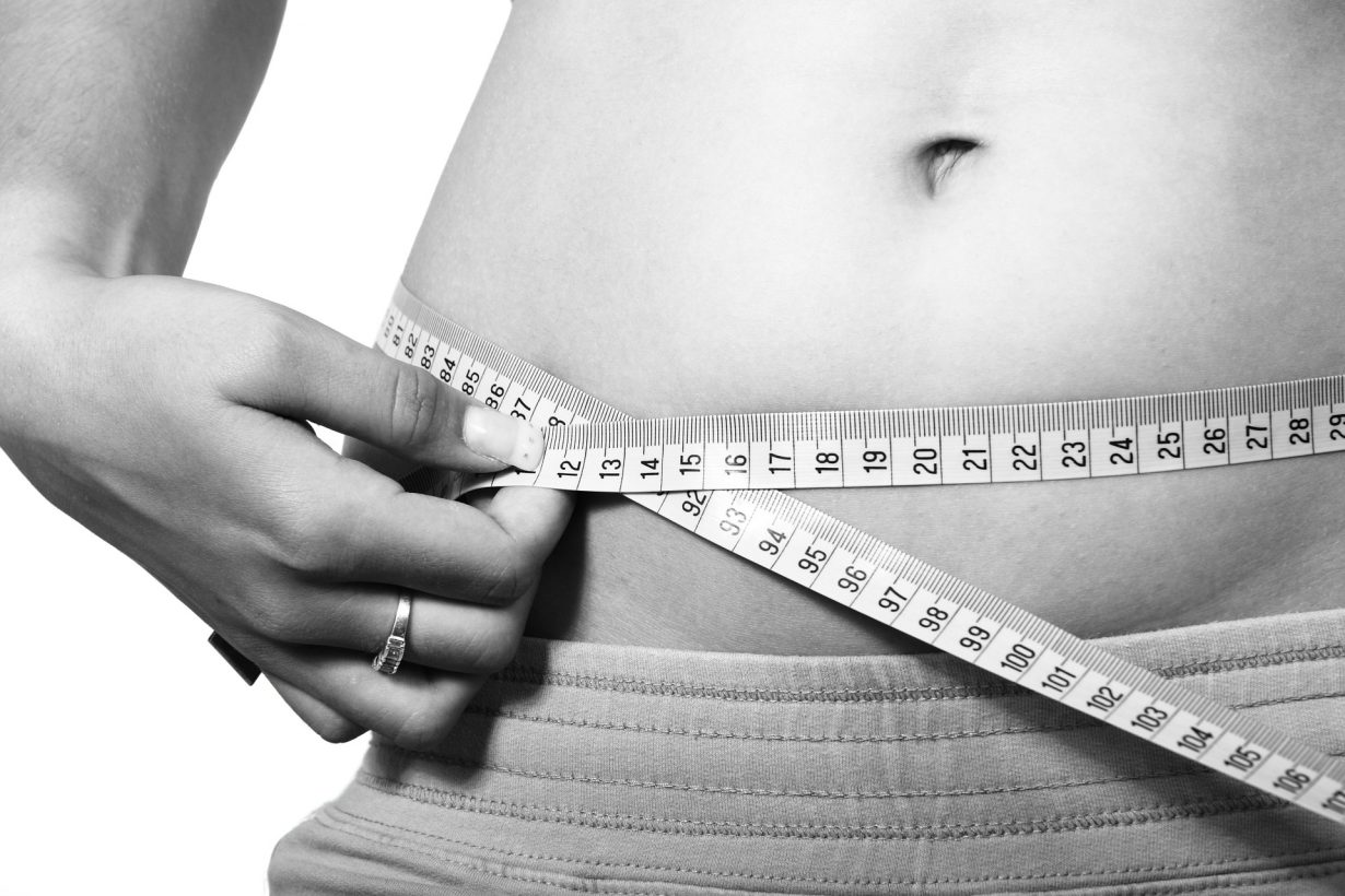 woman measuring her belly with a measuring tape