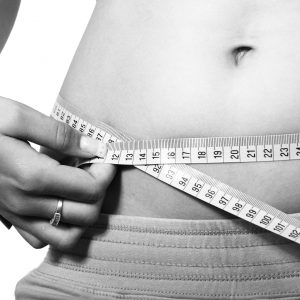 woman measuring her belly with a measuring tape