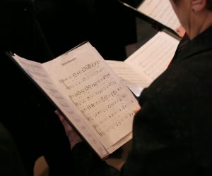 person in a choir holding sheet music