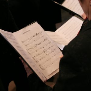 person in a choir holding sheet music