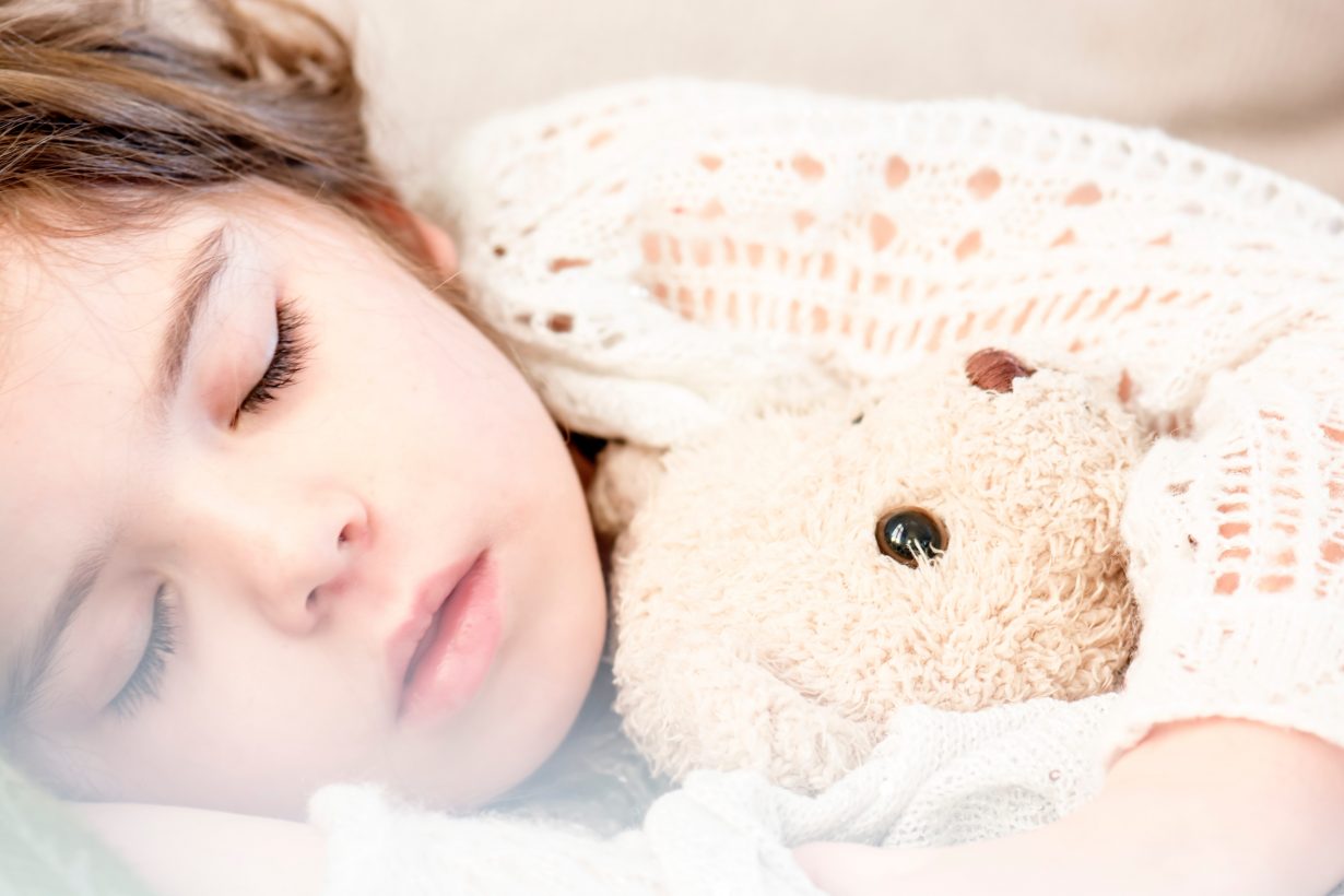 sleeping child holding a stuffed animal