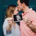 two people kissing holding their ultrasound picture
