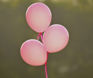 3 pink balloons in a bunch, floating